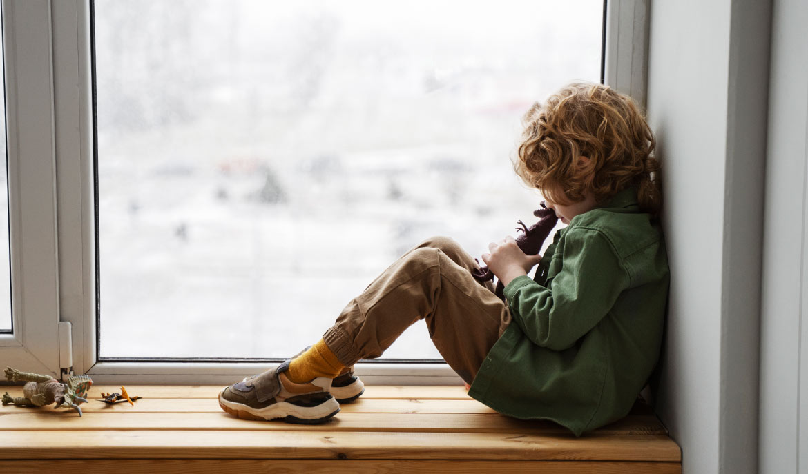 Child sitting on a window ledge - Child Development Signs of Autism Spectrum Disorder (ASD): A blog from Positive Behavior Services